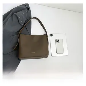 Detail view of large brown leather bucket bag featuring gold logo and metal bottom studs