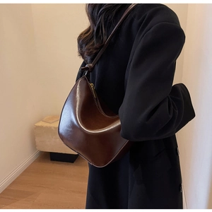 Detailed side view of dark brown crescent hobo bag with knotted shoulder strap and zipper