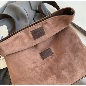 Detail view of brown suede bag showing wide textile strap and velcro closure mechanism