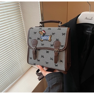 Detail of houndstooth crossbody bag featuring leather handle and dachshund embroidery