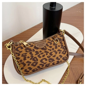 Detail of leopard print baguette bag with brown leather trim and golden metal chain