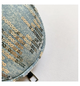 Détail macro du tissu denim bleu avec paillettes argentées et fermeture éclair en métal