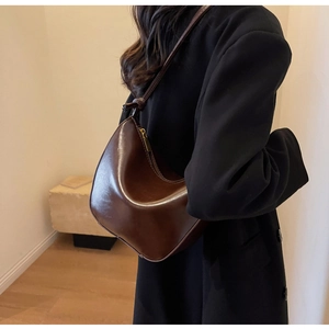 Detail view of glossy dark brown leather hobo bag with gold zipper and stylish shoulder strap