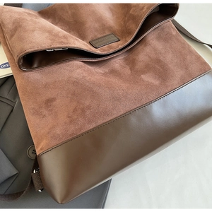 Detail of brown suede and smooth leather stitching bag with embossed logo on flap