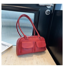 Macro shot of red leather shoulder bag featuring dual front flap pockets and silver zipper