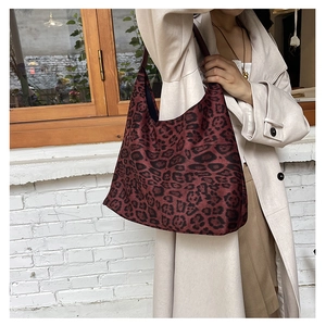 Close-up of leopard print tote bag texture and wide strap on a beige wool coat