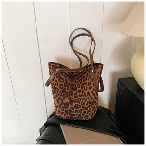 Close-up of leopard print bucket bag with brown leather handles and metallic rivets