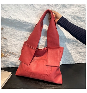 Detailed close-up of textured brick red tote bag featuring geometric circular stitching