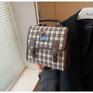 Detail of vintage plaid backpack with embroidery dachshund patch and brown PU leather trim