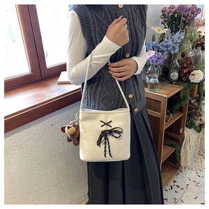 Close-up of beige canvas bucket bag with brown bow knot and cute puppy plush charm