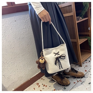 Close-up of canvas shoulder bag with brown ribbon bow and cute plush puppy charm