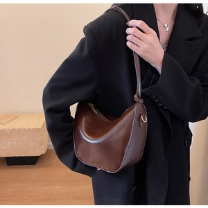 Detail of dark brown polished leather hobo bag with gold hardware and knotted strap