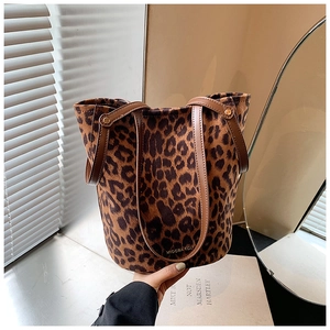 Detail shot of leopard print tote bag featuring brown leather handles and canvas texture