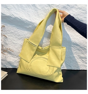 Detail of light yellow tote bag featuring lychee grain texture and circular stitching