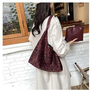 Detail of burgundy leopard print tote bag with matching zippered pouch on shoulder