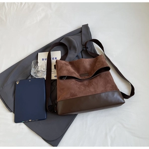 Detail of vintage brown suede leather tote bag on grey blazer with professional accessories