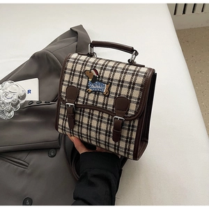 Detailed close-up of retro plaid handbag featuring a cute sausage dog embroidery and leather trim
