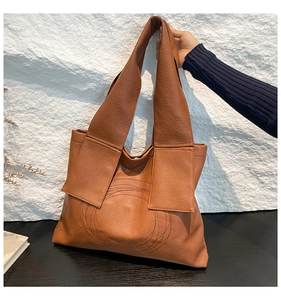 Detail of caramel brown tote bag with decorative circular stitching and smooth PU leather texture