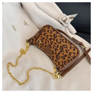 Close-up of leopard print fabric texture with brown leather trim and golden chain strap