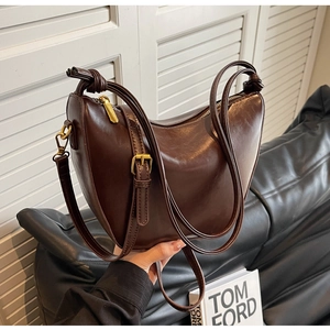 Detail of a dark brown hobo shoulder bag featuring a knotted strap and golden hardware