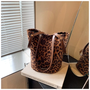 Close-up of leopard print faux fur bucket bag with brown leather trim and metal rivets