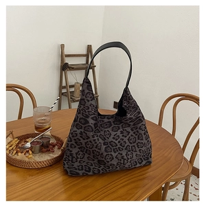 Close-up of leopard print tote bag with black leather handles on a wooden table