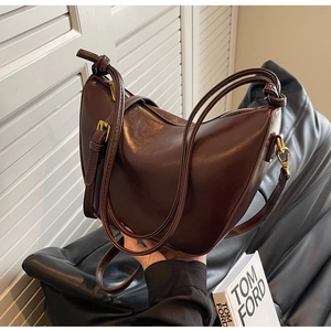 Close-up of a dark brown crescent bucket bag with knotted handle and gold metal zipper detail