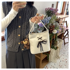 Close-up of white canvas bag with decorative ribbon bow and cute brown puppy plush charm