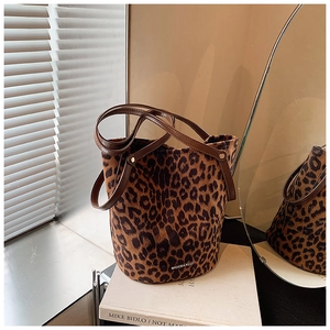 Detail view of leopard print bucket bag with leather strap on a decorative book