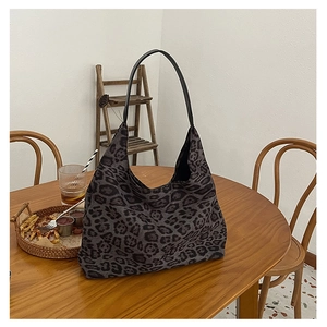 Detail of leopard print tote bag with black leather strap on a cafe wooden table