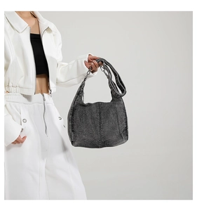 Detail of large washed grey denim hobo bag with adjustable strap and contrast stitching