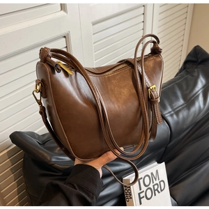 Close-up of matte dark brown PU leather saddle bag with gold zipper and adjustable strap