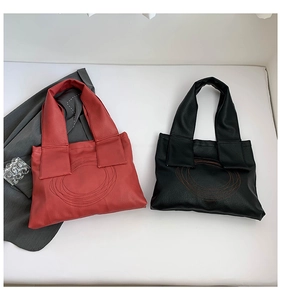 Detail of large tote bags in black and brick red with circular stitching and wide handles