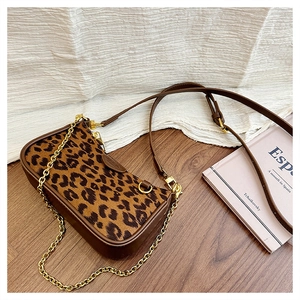Close-up of leopard print handbag with brown leather trim and gold metal chain strap