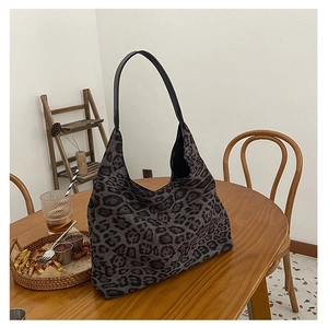 Detail of grey leopard print tote bag with black leather strap on a wooden table