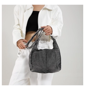 Detail of gray-black washed denim hobo bag showing retro fabric texture and metal hardware