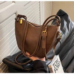 Detailed close-up of dark brown crescent bag showing gold hardware and knotted strap