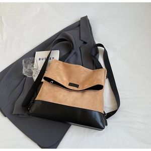 Detail of camel suede and black leather patchwork bag on a grey blazer
