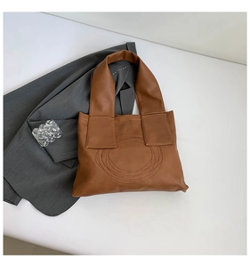 Detail of caramel brown leather tote featuring unique circular stitched pattern and wide straps