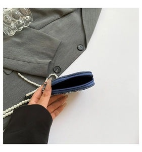 Détail de la mini pochette en tweed bleu avec chaîne en perles et fermeture éclair