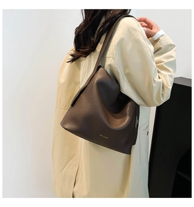 Detail of deep brown faux leather tote bag with fine grain texture and gold logo