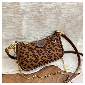 Detail of leopard print suede texture with brown leather trim and gold chain strap