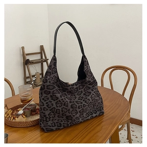 Detail of vintage leopard print tote bag with black leather strap on a wooden table