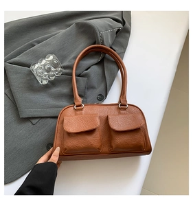 Close-up of brown faux leather shoulder bag with lychee texture and twin front pockets