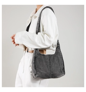 Detail of dark gray hobo shoulder bag in denim fabric with stitching and wide strap