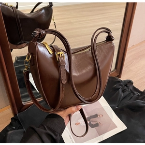 Detail of dark brown leather handbag with gold hardware and stylish knotted handle design