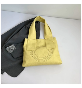 Detail of yellow tote bag featuring artistic circular stitching and textured PU leather