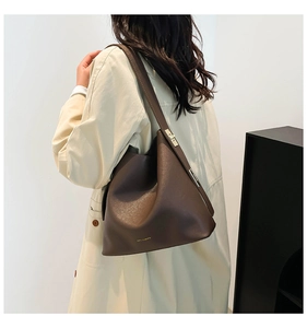 Detail view of large dark brown leather bucket bag showing grain texture and gold buckle