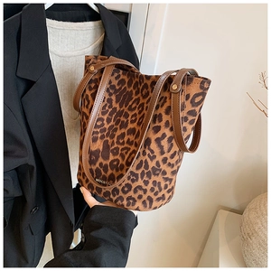 Close-up of leopard print suede bucket bag with leather handles and gold rivet details