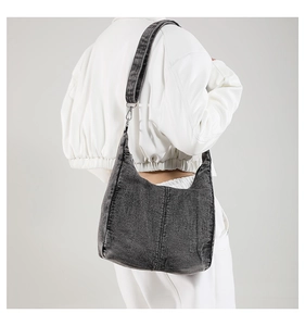 Detail of dark grey washed denim hobo bag showing texture and stitching on model